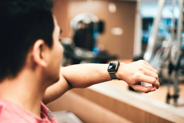 los jóvenes deportistas asiáticos revisan los relojes deportivos después de hacer ejercicio. - body care asian ethnicity body building toughness fotografías e imágenes de stock