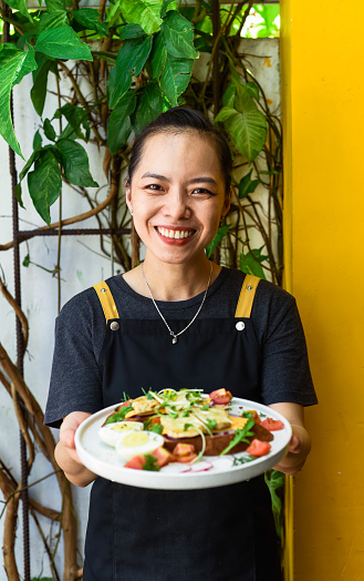 Young vietnamese waitress holding a plate with chicken toast