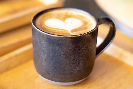 A Close-Up View of a Latte with a Beautiful Heart Shaped Milk Art on Top, Served in a Dark Mug