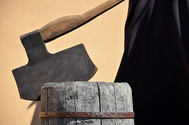Headsman's axe hewed in old wooden chunk Headsman's axe hewed in old wooden chunk executioner stock pictures, royalty-free photos & images