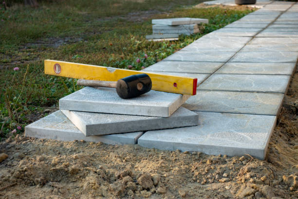 Laying a paving stone or brick. Gray concrete slabs in house courtyard on sand foundation base. stock photo