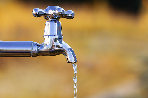 Metal tap with drain water in autumn outdoors