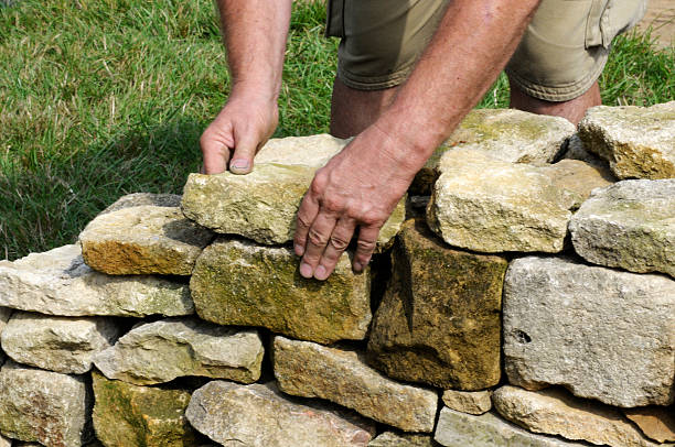 Dry Stone Wall Building Man building a dry stone wall by hand. These are very popular in England in places like Cumbria, Lake District, Yorkshire, The Dales. peak district national park photos stock pictures, royalty-free photos & images