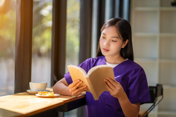 una dottoressa si rilassa, beve caffè, mangia spuntini, legge un libro durante le pause. - clothing protective workwear authority anticipation foto e immagini stock