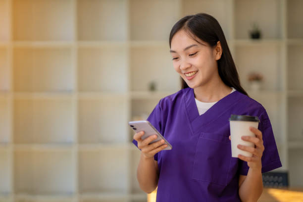 medico donna rilassato che beve caffè parla in chat con gli amici sul tuo cellulare durante le pause. - clothing protective workwear authority anticipation foto e immagini stock