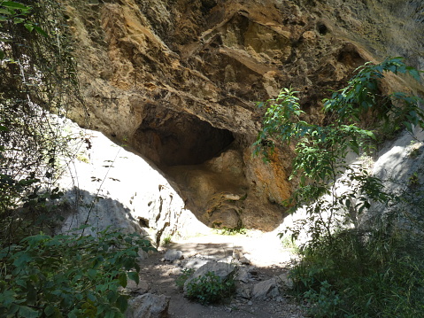 Photo of the entrance to a cave with part of the rocks illuminated by the sunlight. This photograph was taken in the Luberon in Provence.