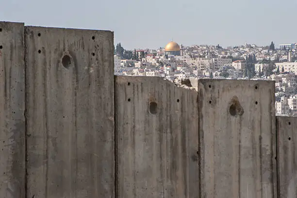 The Dome of the Rock is visible over the Israeli separation wall dividing occupied Palestinian territory in the community of Abu Dis, east of Jerusalem.