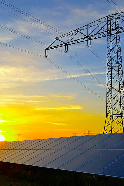 Photovoltaic panel's and electricity pylon at sunset stock photo