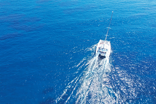 Experience the serene beauty of catamaran sailing as these twin-hulled marvels gracefully traverse tranquil waters. This aerial view encapsulates the essence of peaceful exploration on the open sea