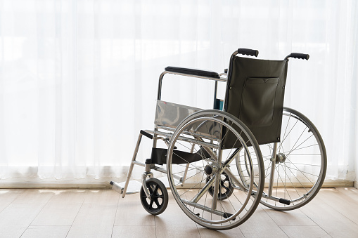 Wheelchair placed for person with disability in empty room of nursing home. Bright space with support walker and assistance in elderly assisted living center, health rehabilitation.