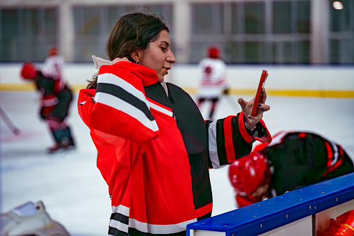 Women's Ice Hockey Offensive Player applies makeup by looking at phone screen