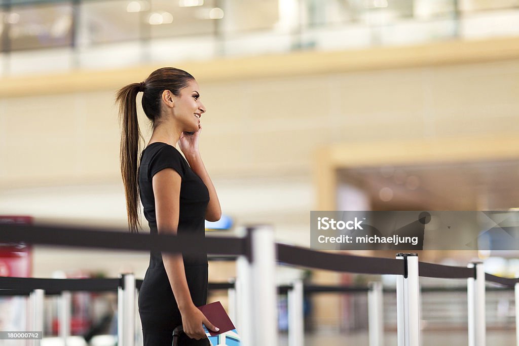 Donna d'affari parlando sul cellulare in aeroporto - Foto stock royalty-free di Fare la fila