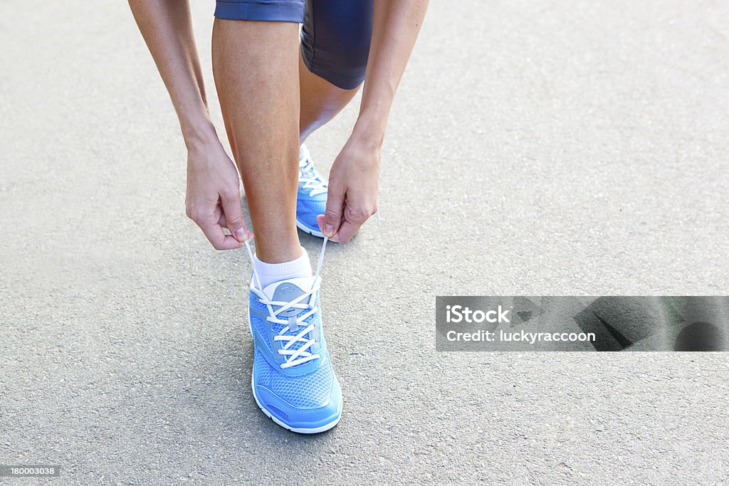 Detalhe de Jovem mulher fazer o calçado esportivo. - Foto de stock de Adulto royalty-free