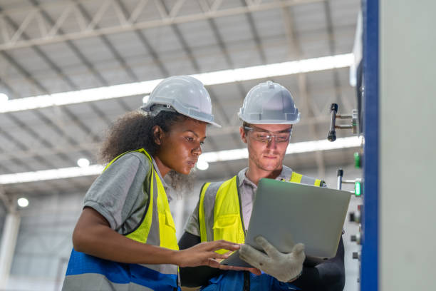 istock Man and female engineer in uniform wearing helmet safety using laptop inspecting and controlling ink color printing carton package and cutting corrugated sheet cardboard box machine at paper factory 1800036324