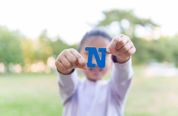 child holding letter "n" - n train стоковые фото и изображения