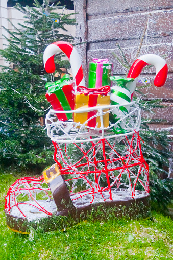 Christmas gifts inside Santa Claus large boot,   , candy walking canes, Christmas decorations outdoors, fir tree leaves.