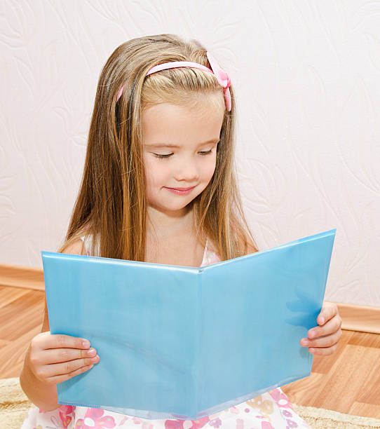 istock Cute smiling little girl reading a book 180011771