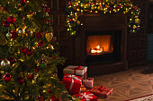Classical Christmas decorated interior living room library with fireplace. Christmas tree with red golden ornament decorations. Modern classic style interior design apartment. Christmas eve at home.