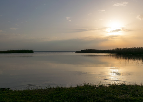 view of the lake before sunset, sunbeams through the clouds, calm water surface, lake meadow foreground, Lake Burtnieki, Latvia