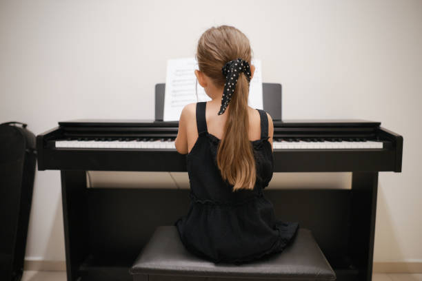 リビングルームでピアノを弾く美しい小さな幼児の女の子。音楽楽器を演奏する学習を楽しんでいるかわいい就学前の子供 - piano keyboard instrument one person piano key ストックフォトと画像