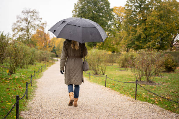 istock woman walking through public park in rain 1800160993