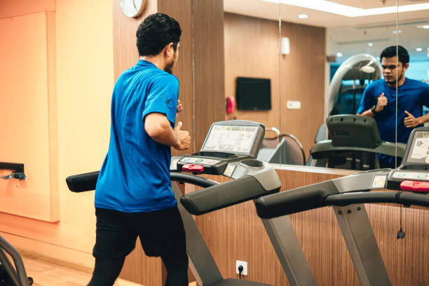 joven atleta asiático que corre o trota en la cinta de correr en un club deportivo del hotel - body care asian ethnicity body building toughness fotografías e imágenes de stock