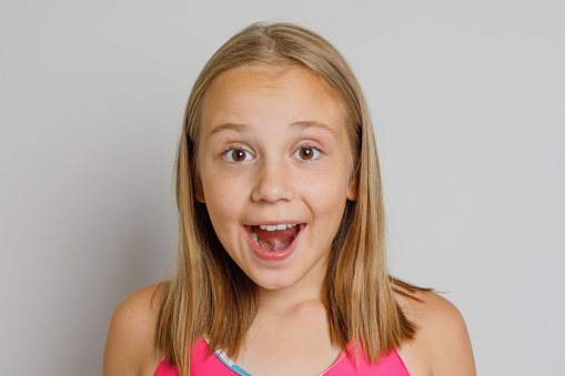 Photo of toothy beaming schoolgirl with ponytails wear yellow pullover arms on head look empty space isolated on khaki color background.