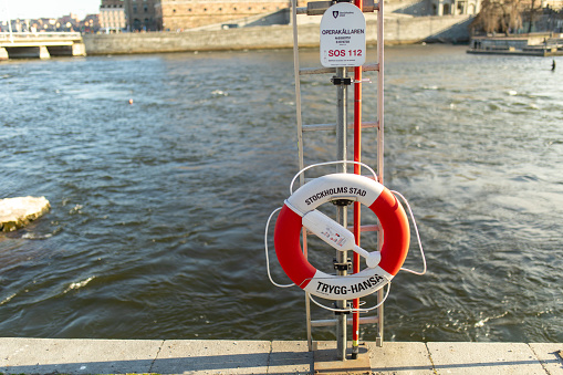 Stockholm city center, Sweden – April 15, 2023: Lifebuoy hang on the pillar next to the river or sea in Stockholm. Safety equipment