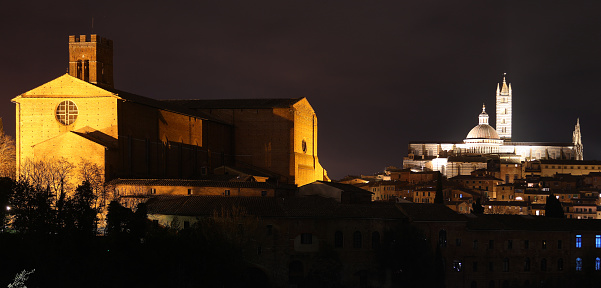 night panorama of the city of Siena in Italy with the cathedral and the church of San Domenico