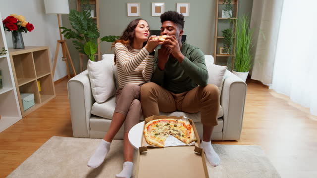 Young couple enjoying pizza at home