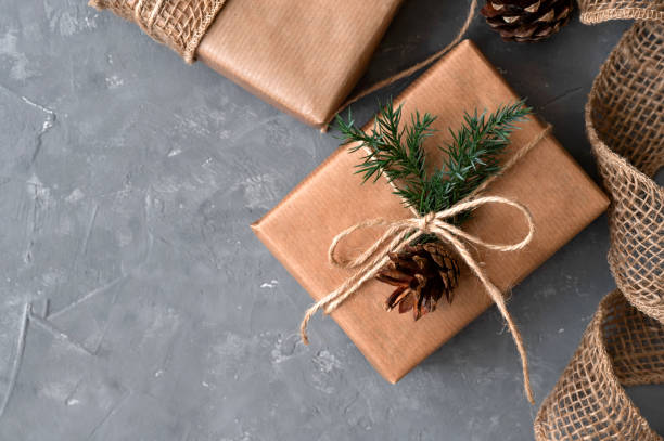 istock Aesthetic Christmas presents on gray table background. Brown gift boxes decorated with crafter paper, conifer twigs and pines. Sustainable ecological winter holiday celebration concept 1800314051