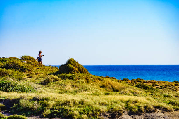 istock Woman walk on seashore, take photo with camera 1800331523