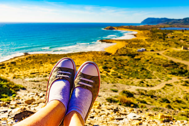 Female feet against mediterranean sea coast landscape. Murcia region, Calblanque Regional Park in Spain. Hiking, active lifestyle.