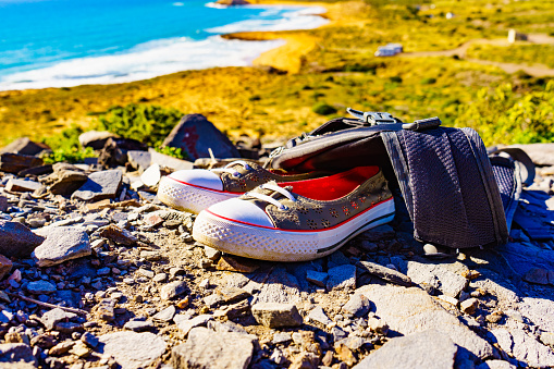 Shoes and backpack, summer walking equipment on mediterranean sea coast. Murcia region, Calblanque Regional Park in Spain. Hiking, camping, active lifestyle.
