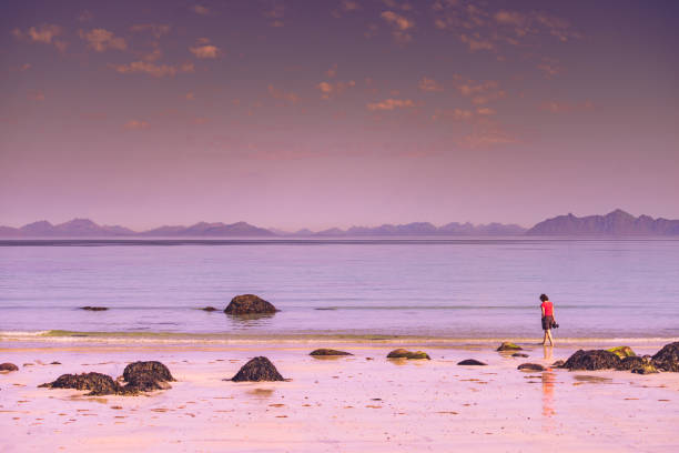Coastal landscape of Coral Strand Beach, Connemara, Ireland, showcasing rugged rocks and lush green hills leading down to a fog-shrouded sea