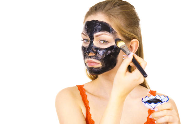 istock Woman applying black mask to skin face 1800383003