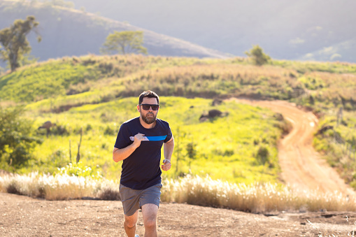 A man running outdoors amid a beautiful landscape. An image to inspire sports and wellness. Excellent for sports events campaigns