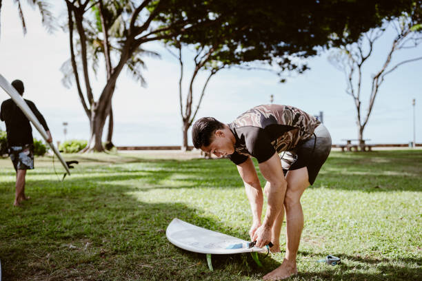 istock Active multiracial man waxing surfboard in grassy beach park 1800407793