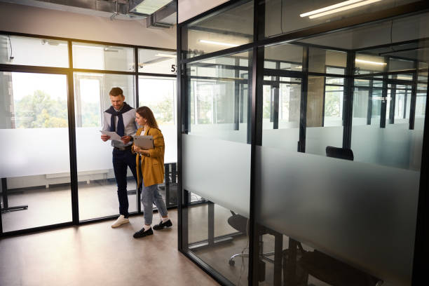 istock Female and male are looking through work documents in office corridor 1800415591