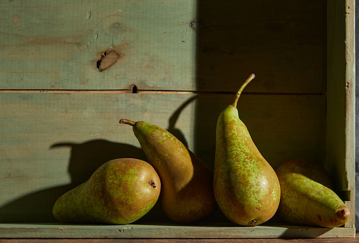 Image of Still Life with a stack of green Pears. Rustic wood background, antique wooden table.