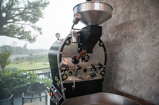 Coffee roaster machine with outdoor cafe view. This automated machine delivers uniform roasts through gentle processing and efficient mixing