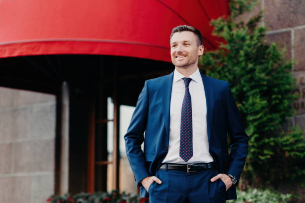 istock Confident businessman in a sharp suit smiling outside an upscale establishment with a red awning 1800436792