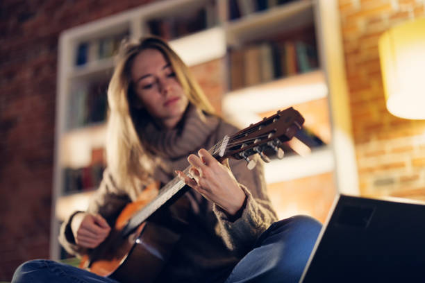 istock Teenage girl practicing playing guitar at home 1800438420