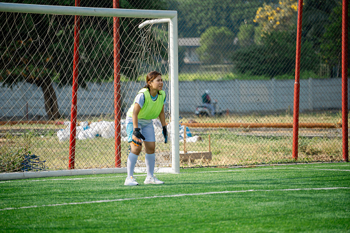 Determined female goalkeeper standing in goal. Sportswoman in colorful uniform getting ready to catch ball. Sport, leisure, active lifestyle concept.