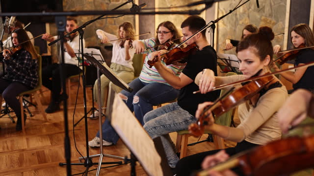 A large group of music academy students practices harmony and playing instruments