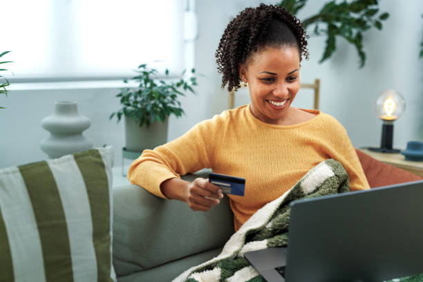 istock Smiling woman shopping online while using laptop at home 1800440674