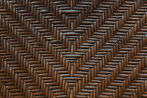 A close up of a woven wood surface texture and pattern. a handmade woodwork furniture in brown color, antique and old with high details. A similar and seamless symmetrical pattern.