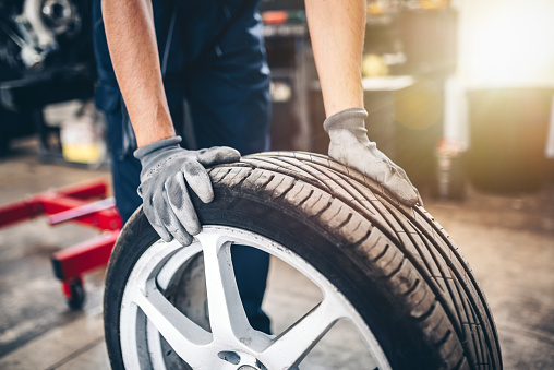 Car tire shop and service - mechanic holding a tyre. Changing of tyres.