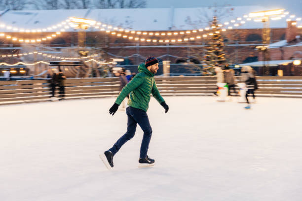 istock Focused man gliding on an ice rink with holiday lights and a Christmas tree. 1800443191