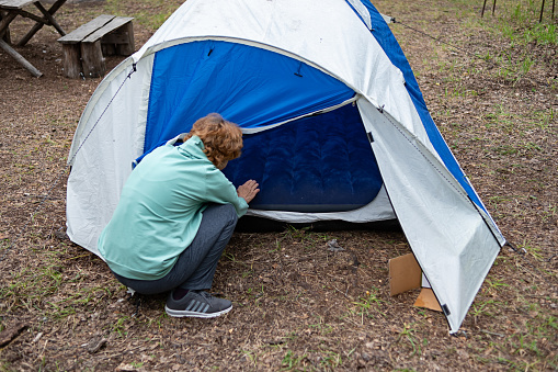 A woman sets up a tent in the forest. Journeys.